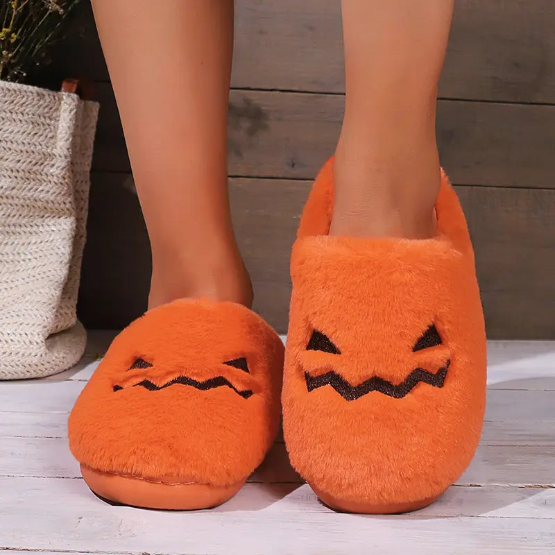 orange plush pumpkin Halloween indoor slippers with black embroidered facial features made of soft fabric for cozy indoor use