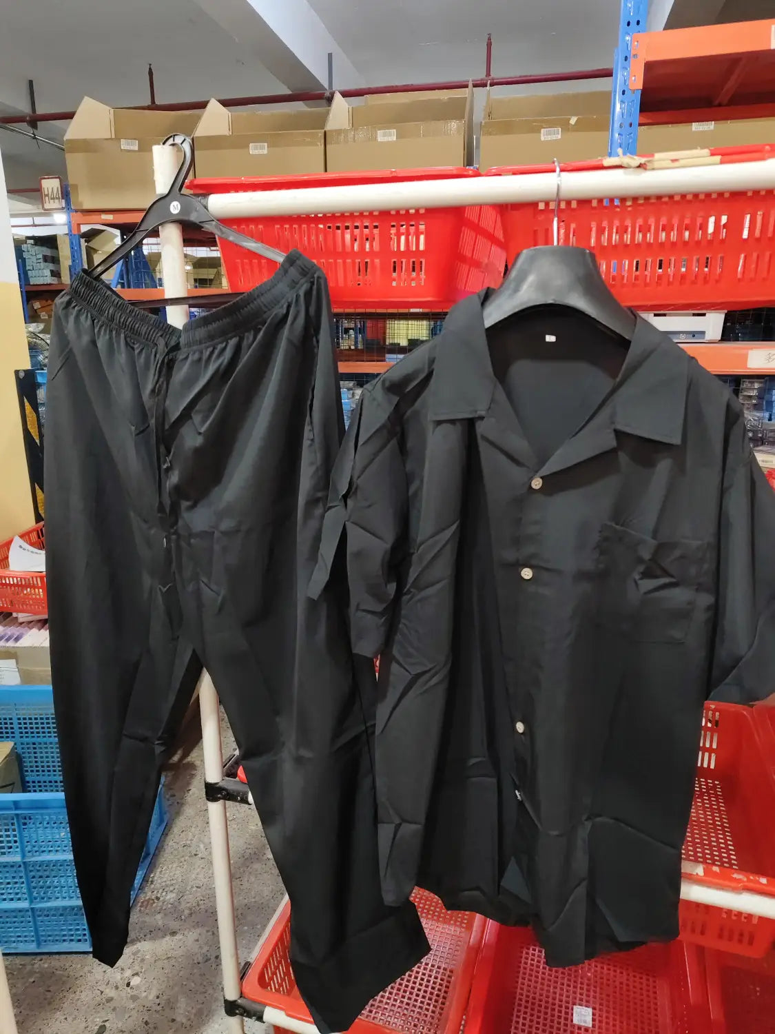 black cotton button-up shirt with short sleeves and collar hanging on black hanger from men short sleeve shirt and trousers set product.