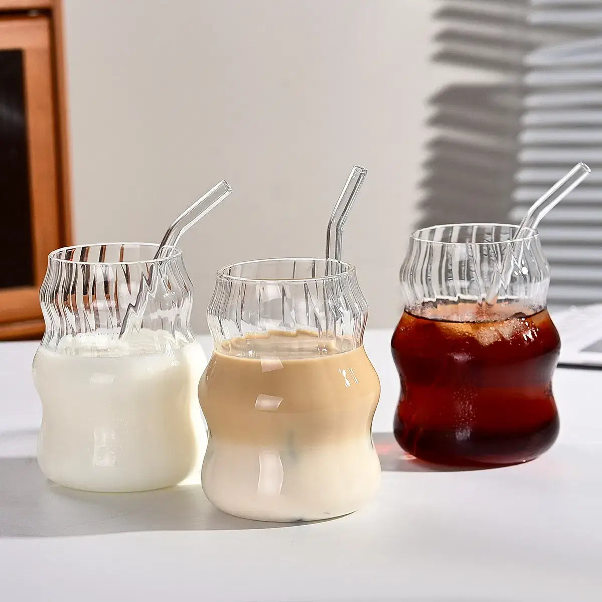Drei klare gerippte Glasbecher mit geschwungenen ergonomischen Formen und passenden transparenten Strohhalm-Einsätzen aus einem gerippten Glasbecher-Set mit Strohhalmen, 6-teiliges Set, 19 oz.