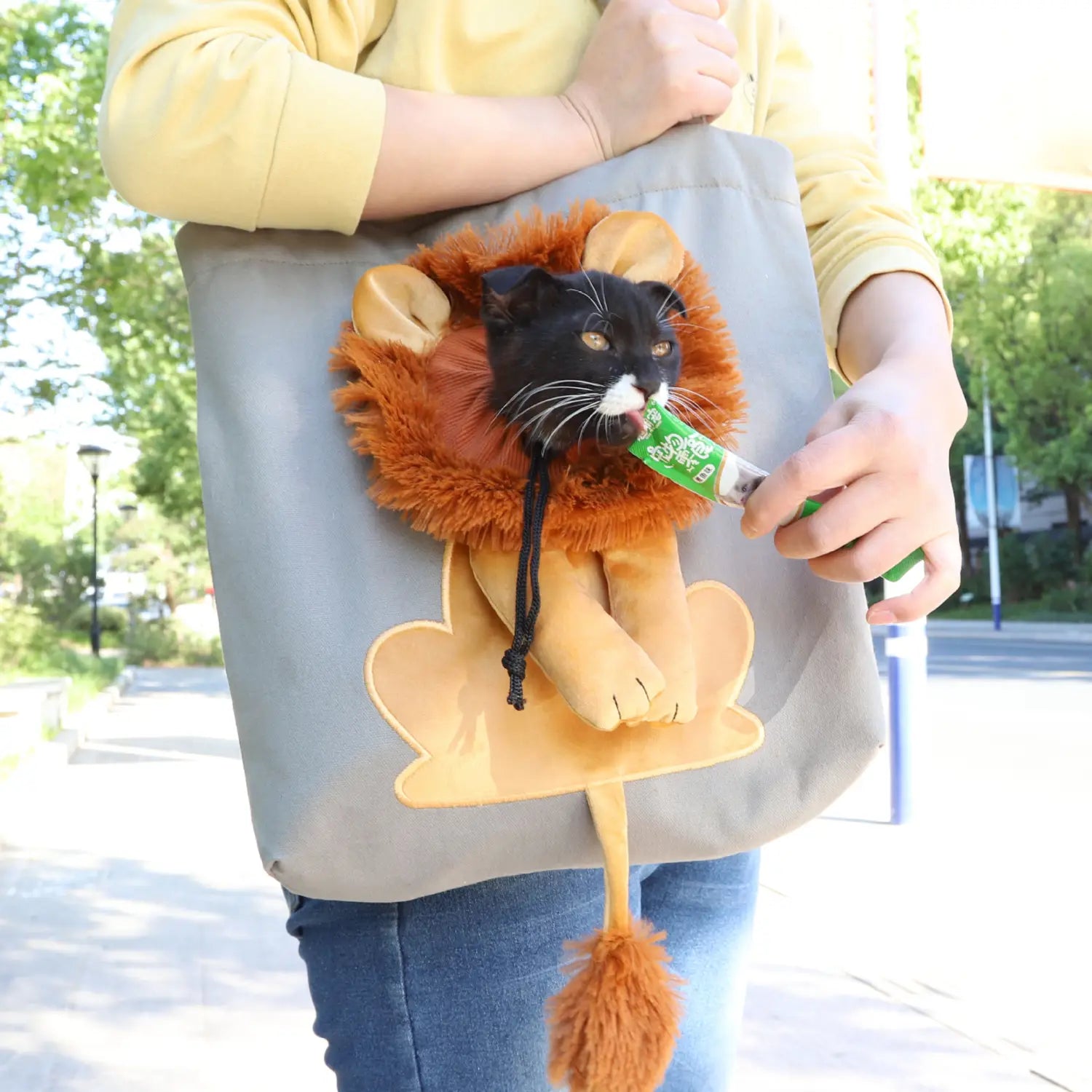 Gray fabric cat carrier bag with plush lion design featuring orange fur tan ears and tail and a black face with white muzzle for portable pet transport.