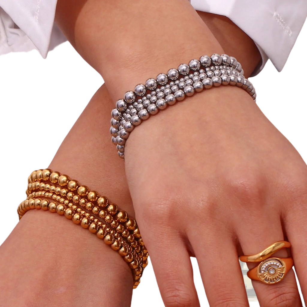 Stacked silver and gold 18k gold plated stainless steel elastic bead bracelets with a polished metallic finish