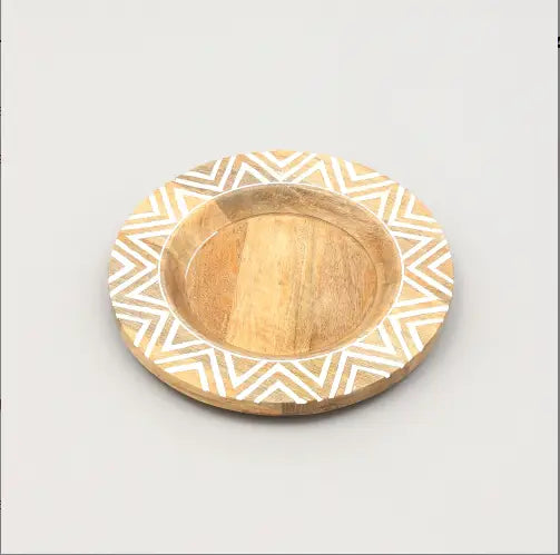 Une assiette plate ronde en bois, avec un centre en bois naturel et un bord extérieur en forme de chevron géométrique blanc, fabriquée à la main pour un usage en table rustique.