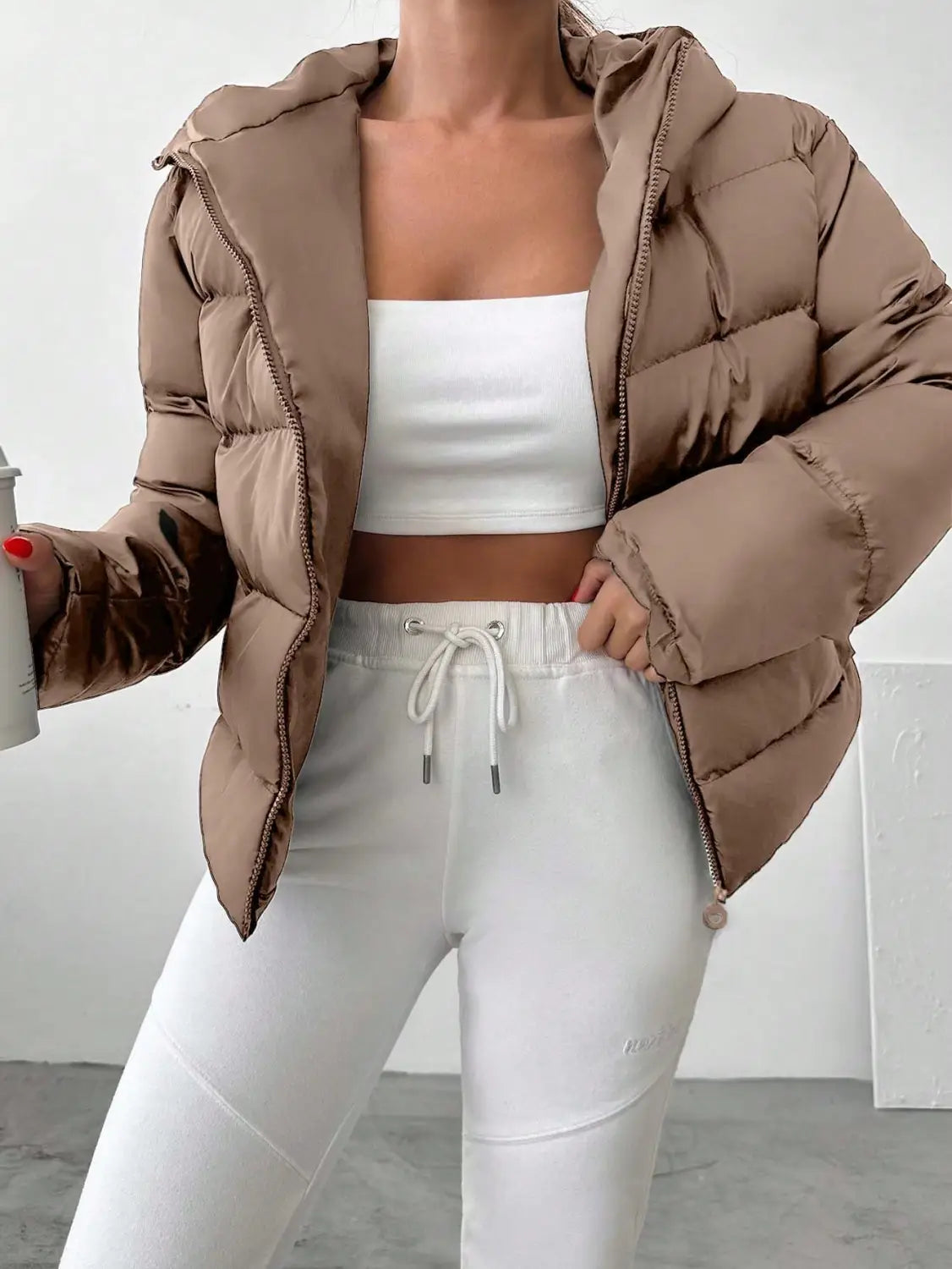 A cozy beige women’s hooded puffer jacket with a quilted design and matching zipper accents.