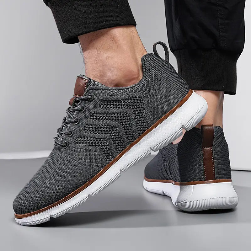 Gray mesh sneakers for men with brown leather accents and a white rubber sole designed for casual flying woven shoes.