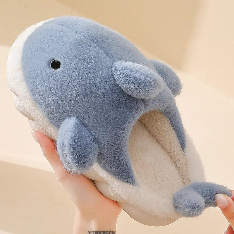 Soft blue and white plush dolphin-shaped shark slippers featuring a cozy fuzzy texture for comfortable indoor use.