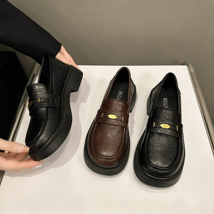 black leather loafers with thick platform sole and gold-tone hexagonal buckle detail visible from the front