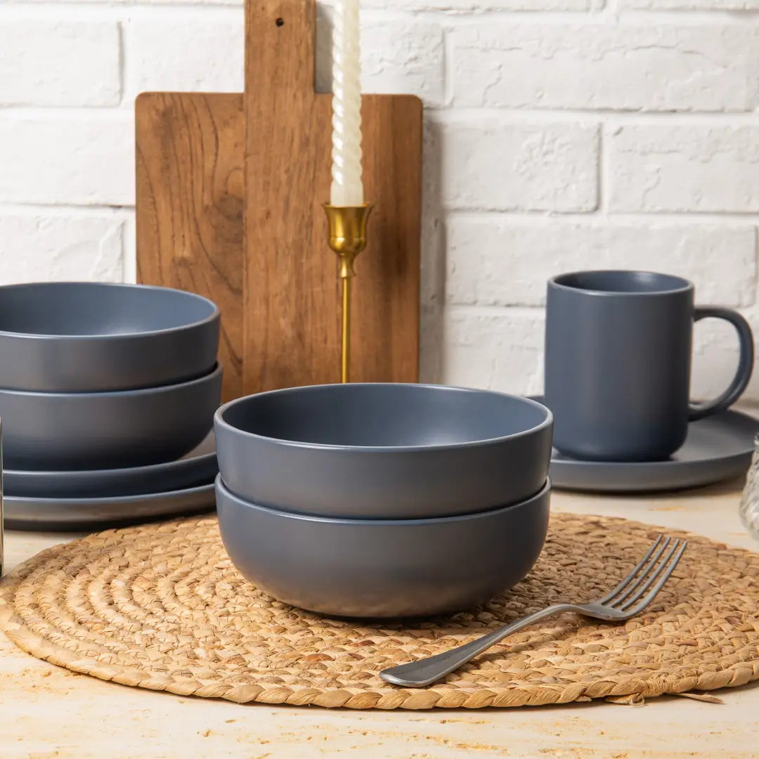 Stack of matte gray ceramic bowls from a 12-piece stoneware dinnerware set with matte glaze service for 3.