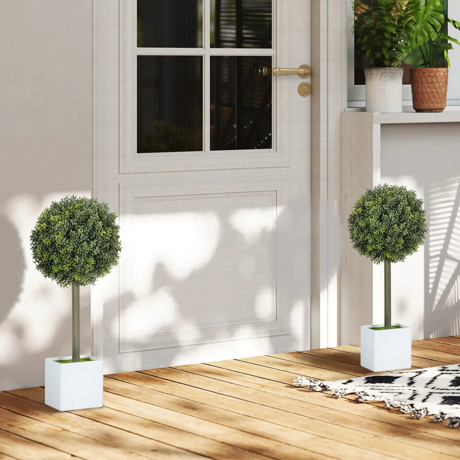 Jardinera cuadrada blanca que contiene una bola redonda de boj artificial tipo topiario en una maceta blanca, de un set de dos.