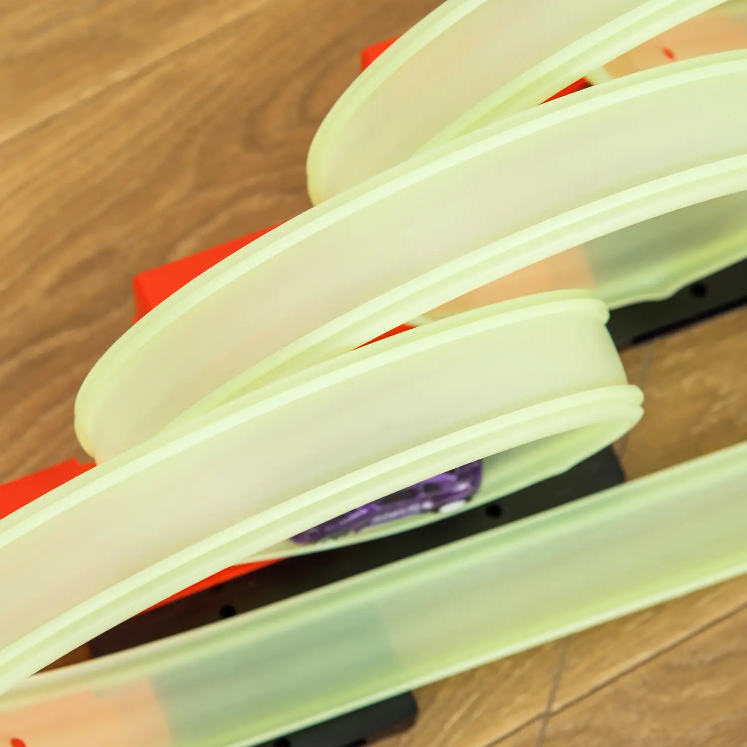 des éléments de piste en plastique vert lumineux pour un circuit de course jouet araignée avec boucle pour jouer avec une voiture.