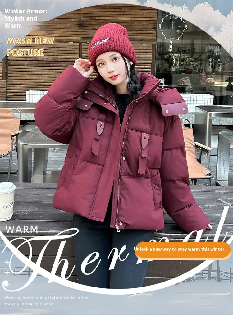Veste courte matelassée à capuche pour femme bordeaux avec fermeture éclair frontale et plusieurs poches à rabat conçues pour l’habillement d’hiver chaud.