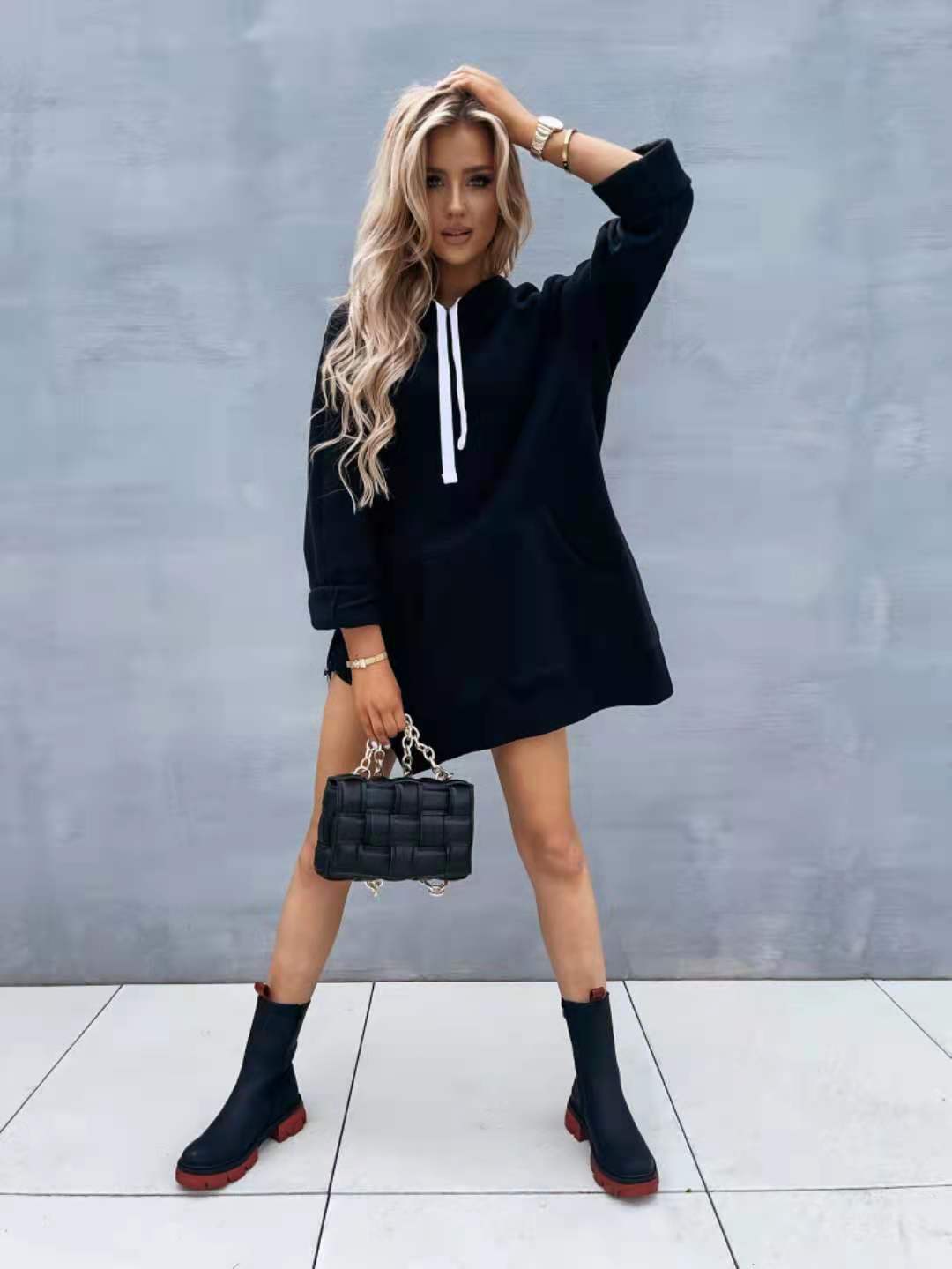 Black quilted handbag with silver chain strap paired with oversized mid length hooded sweatshirt dress with pockets.
