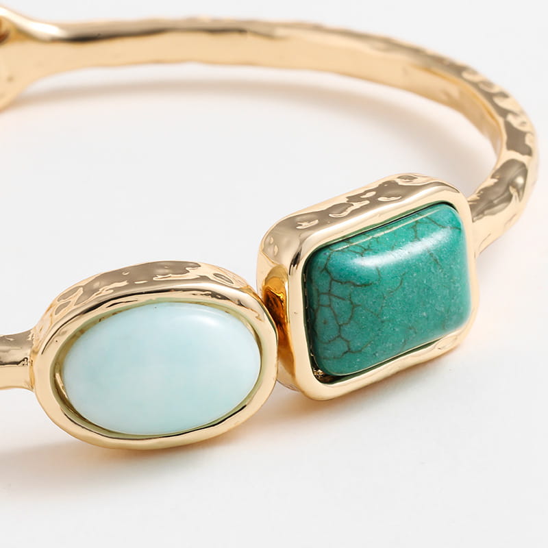 Vintage hammered gold bangle featuring a light blue oval gemstone and a teal rectangular turquoise stone set in textured gold bezels.