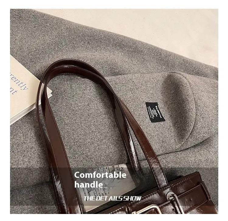 Brown faux leather buckle shoulder bag with a glossy finish, structured handle, and bow charm.