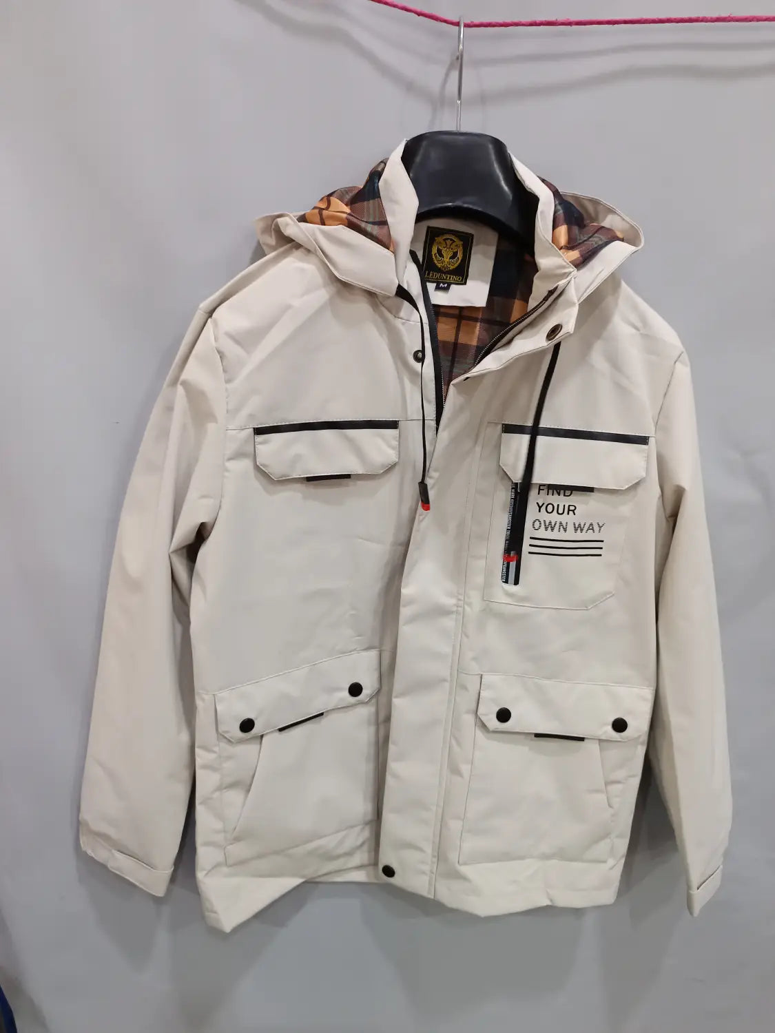 Men winter hooded parka coat in cream color with black trim plaid lining front pockets and a find your own way patch.
