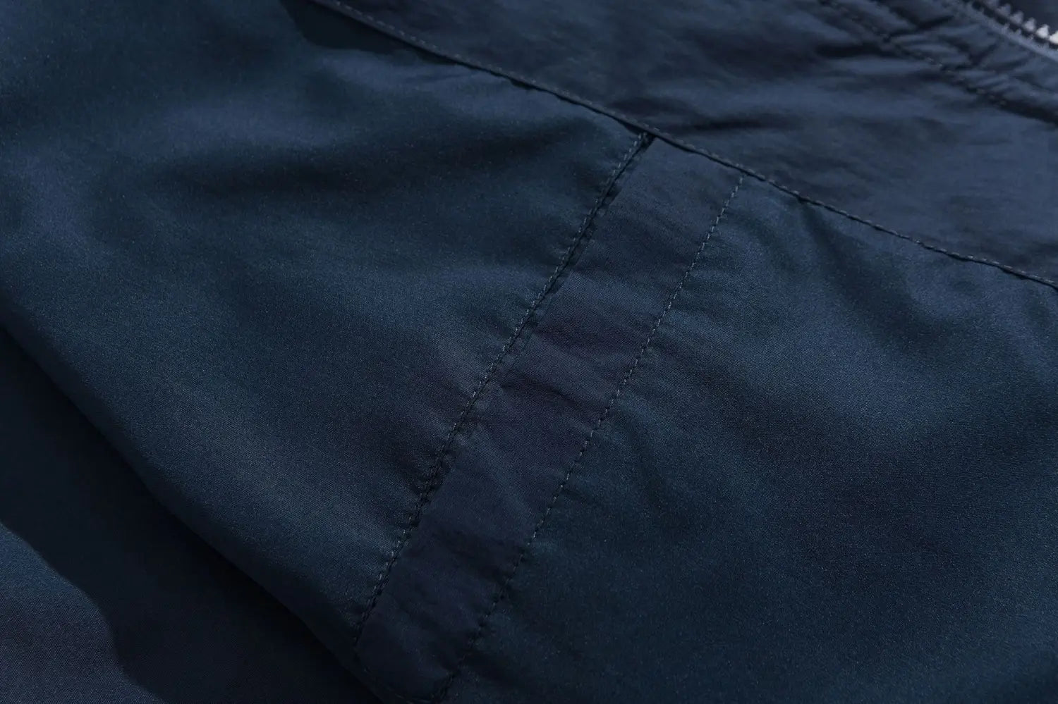 Veste coupe-vent ample en nylon bleu marine foncé à blocs de couleurs brodés, avec un discret piquage diagonal.