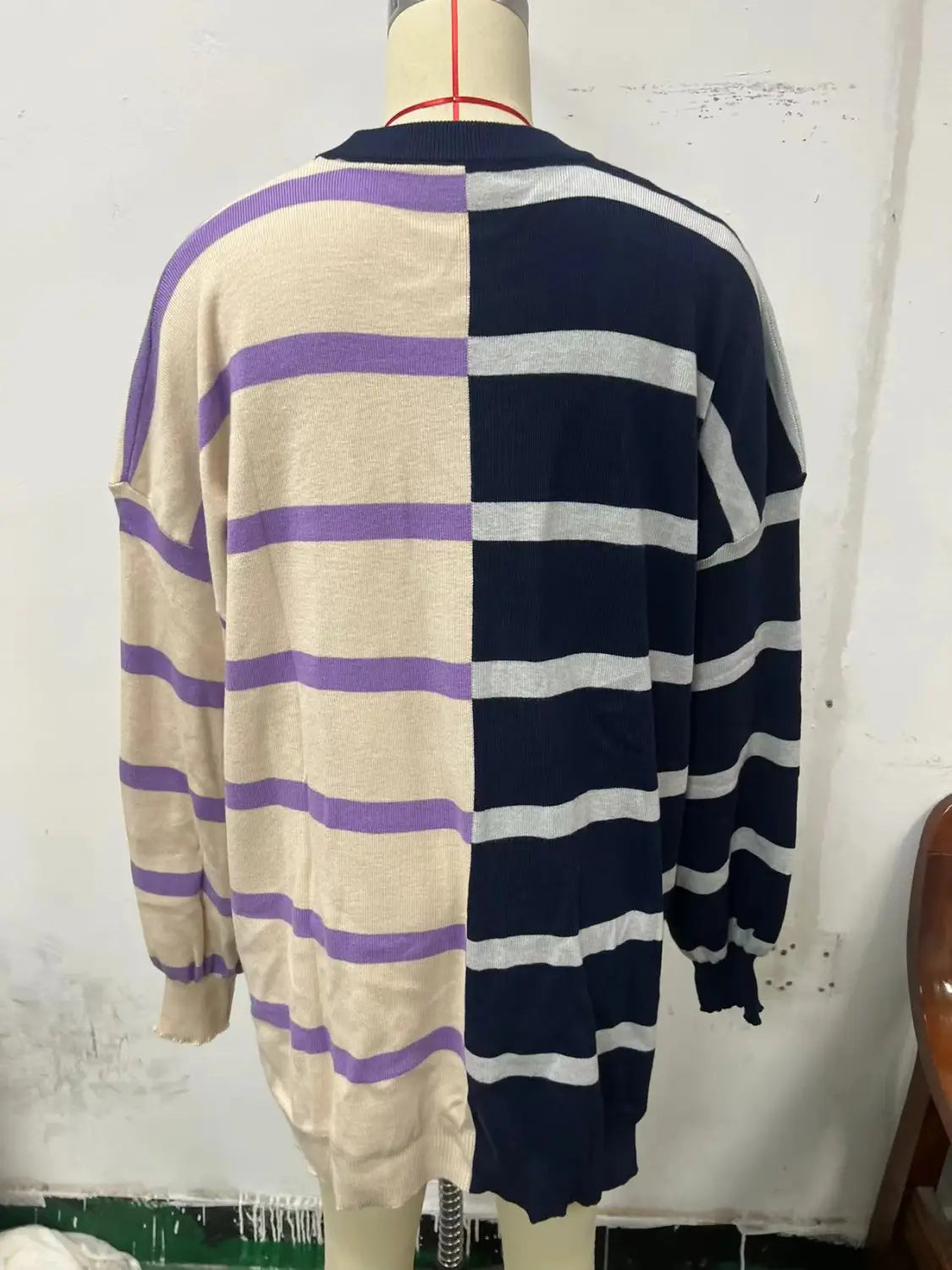 A cozy women’s oversized long-sleeved knit sweater with a split design featuring cream and purple stripes on one side and navy blue and white stripes on the other.