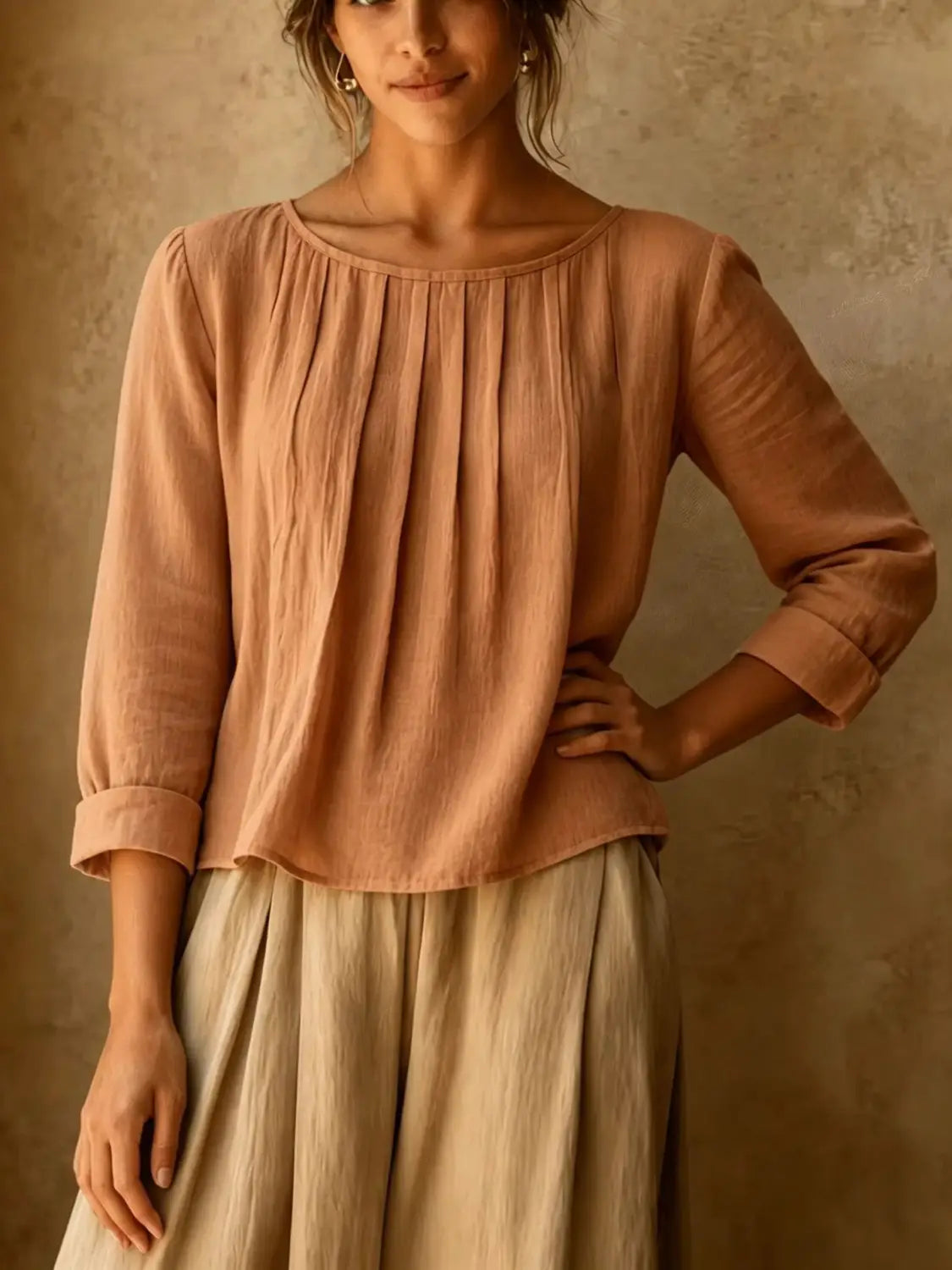 Une blouse en lin et coton pour femmes, couleur rose poudré, avec une coupe ample et une encolure froncée, manches à la longueur trois-quarts.