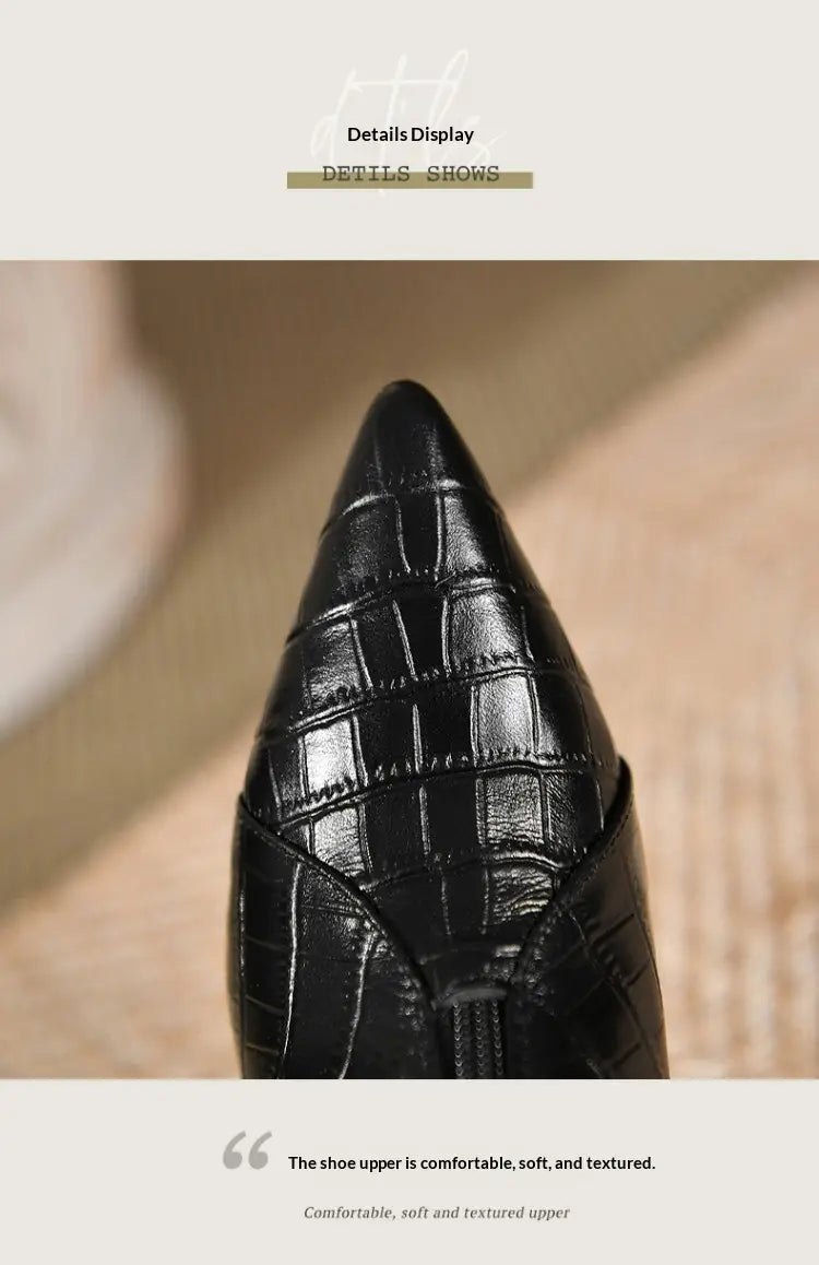 Black crocodile-embossed leather high-heeled stiletto ankle boot with a pointed toe shown from the back side.