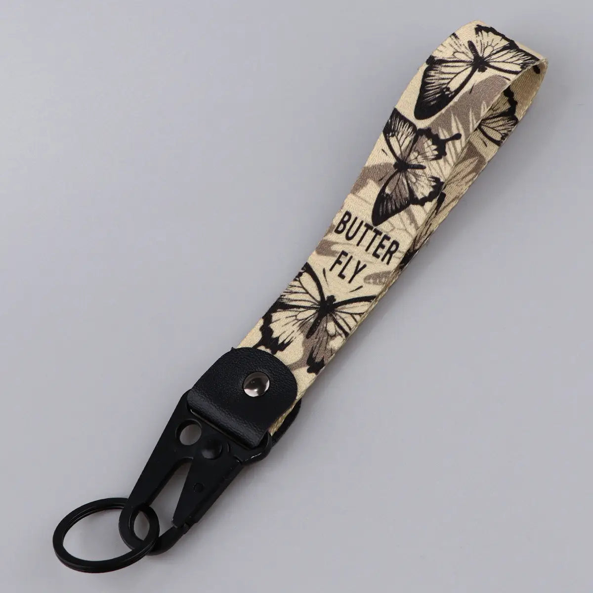Beige fabric butterfly wrist strap keychain with black butterfly and butterfly text design featuring a black metal carabiner clip Tk57.