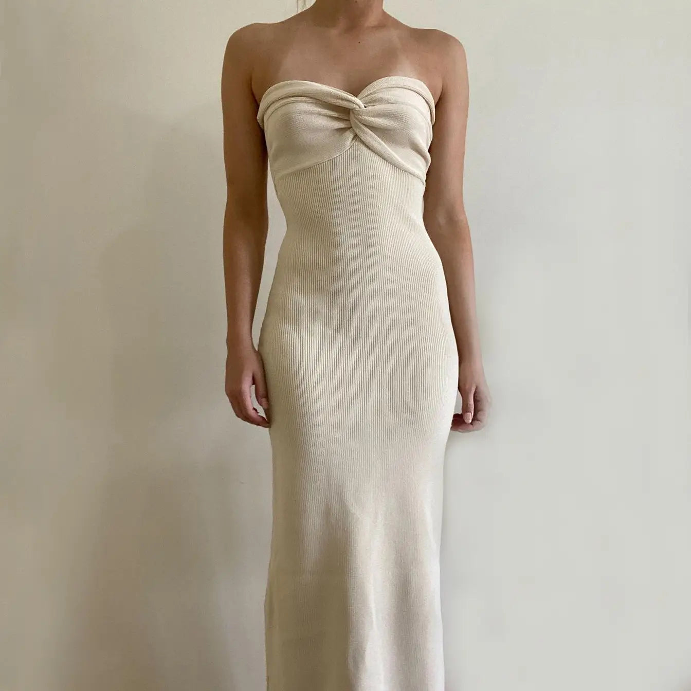 Off shoulder knotted ribbed knit midi dress in cream color featuring a strapless design and twisted knot detail at the bust.