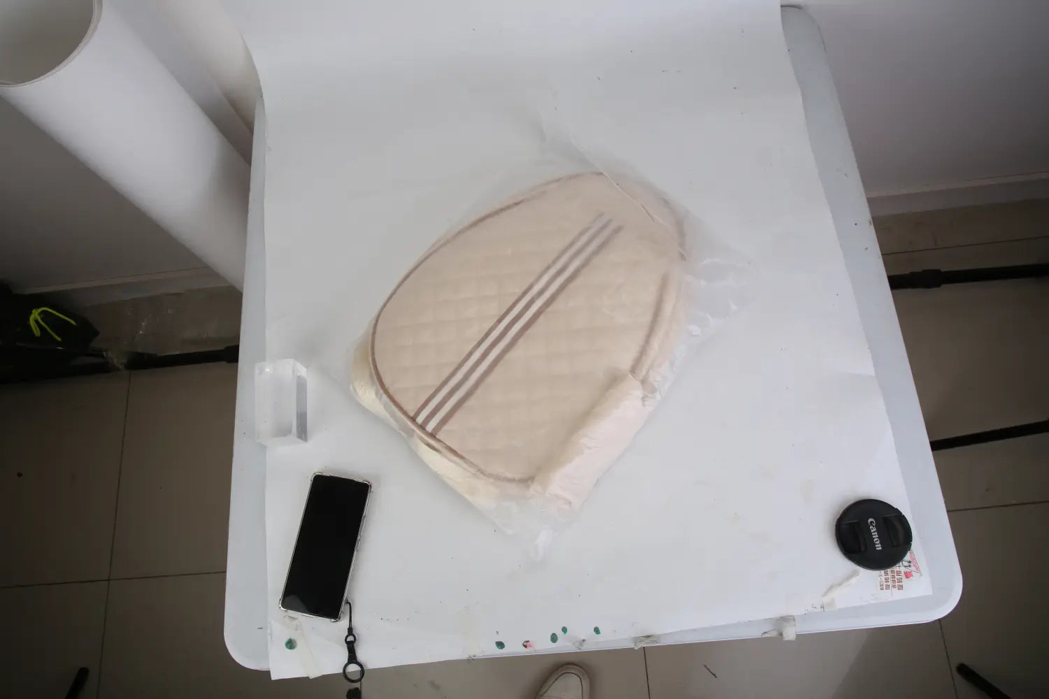 Sac bandoulière pour pickleball matelassé beige, imperméable, avec trois rayures brunes parallèles à l’avant et une poche humide recouverte d’un film plastique transparent.