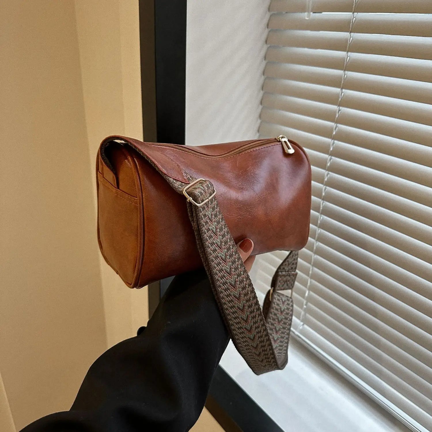 Retro leather crossbody bag in brown leather featuring a woven patterned strap and gold-tone hardware.