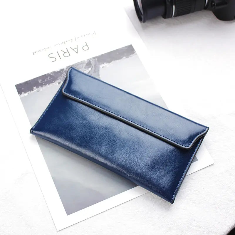 Deep blue leather long wallet with a slim minimalist design and contrasting black stitching made from cowhide perfect as a clutch.