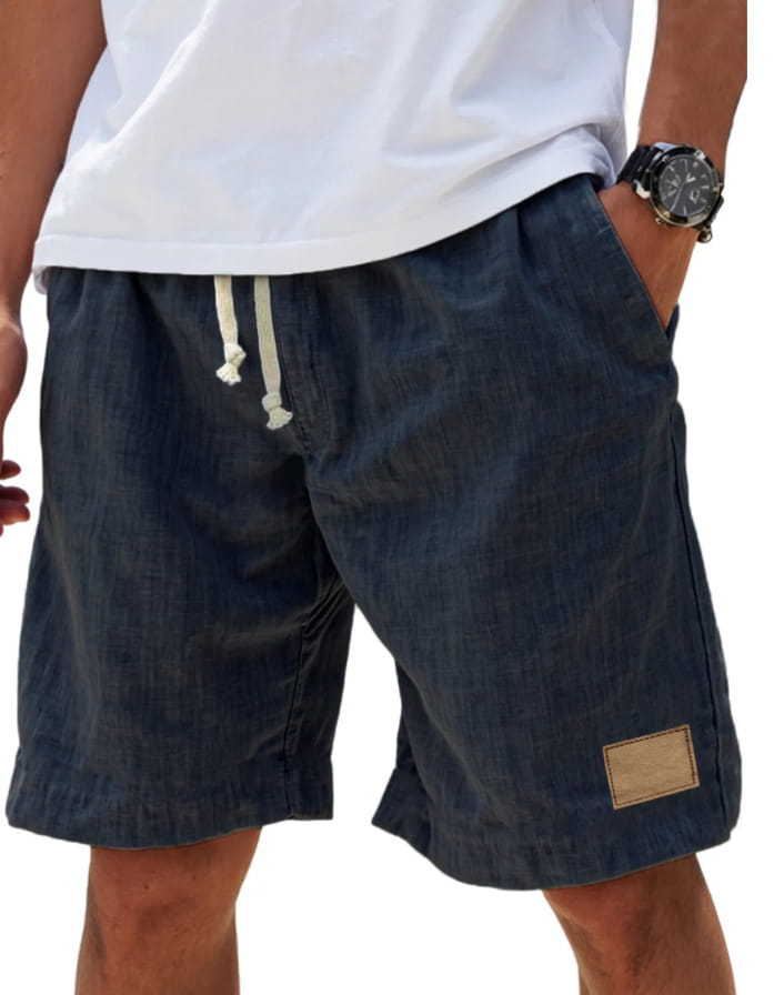 Men linen holiday shorts in dark blue denim with white drawstrings and a tan patch on the side featuring a breathable loose fit retro design.