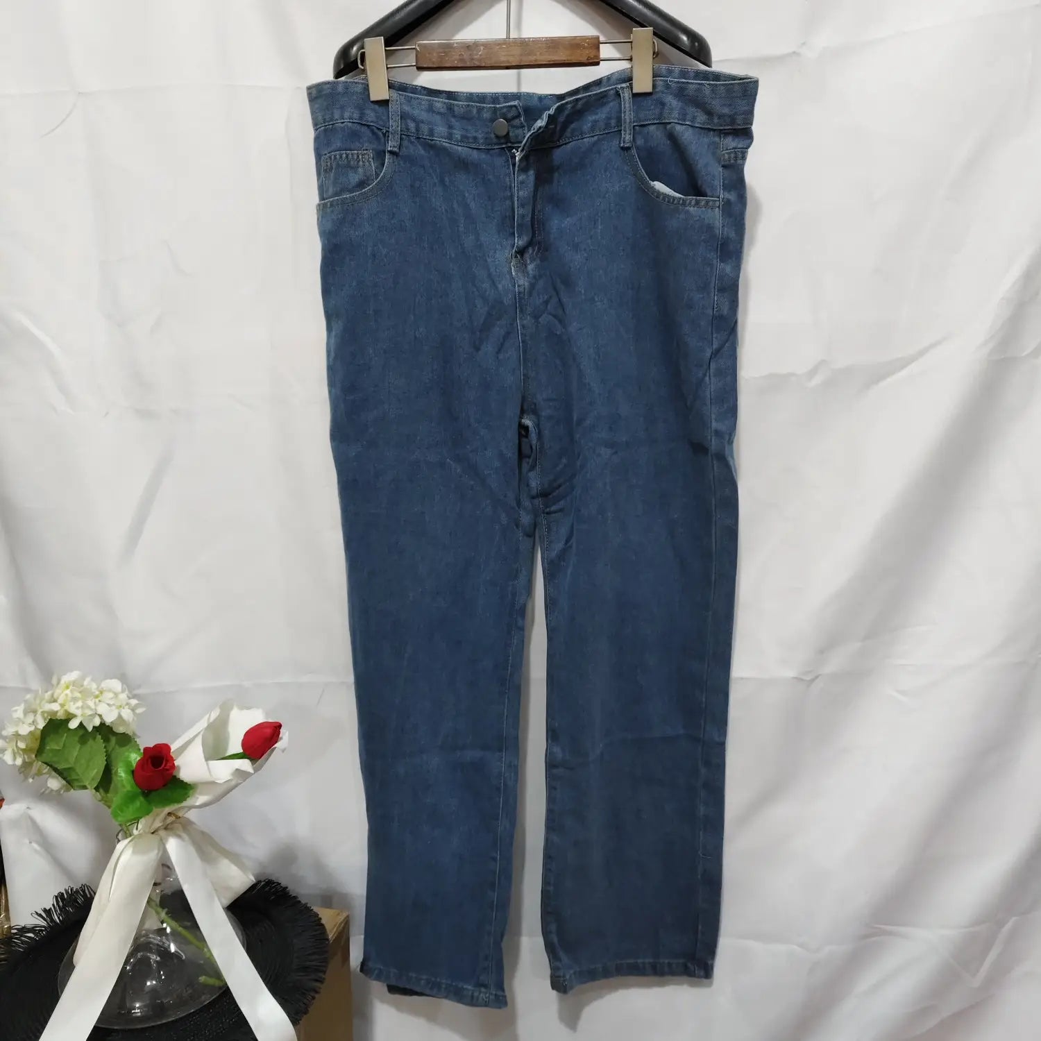 Jeans de mezclilla (denim) lavada de pierna recta en azul para mujer, colgados en una percha de madera.