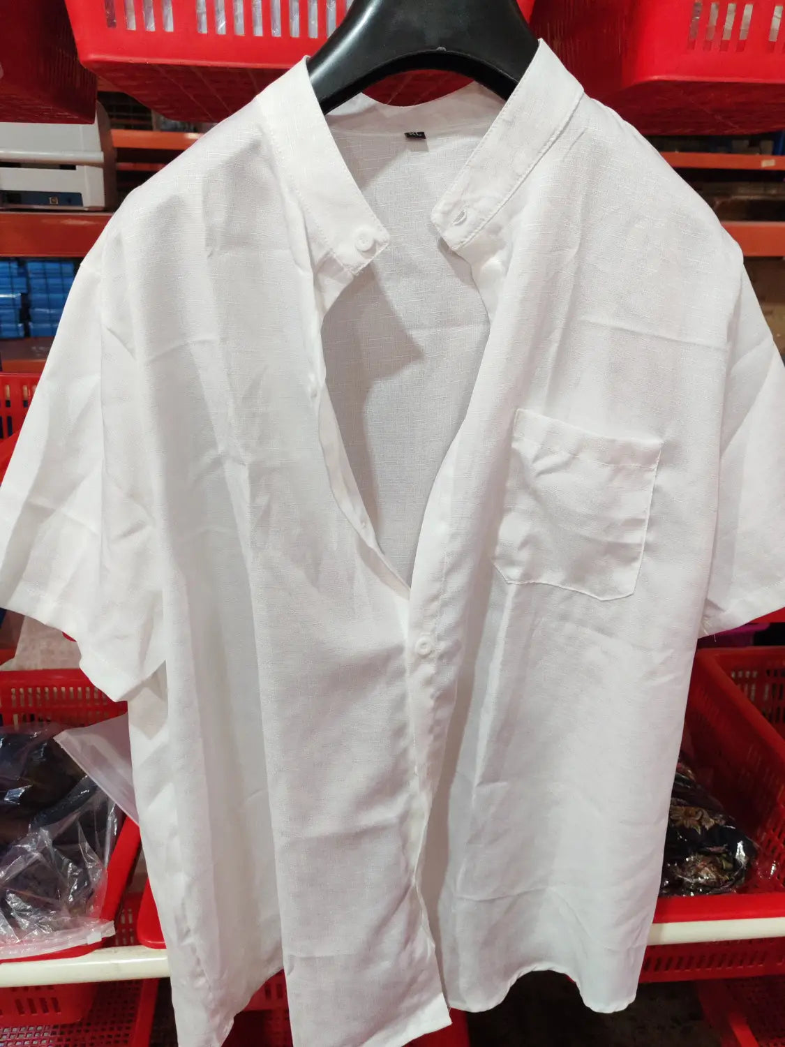 White short-sleeved button-up shirt with collar and chest pocket hanging on a black hanger for mens mandarin collar short sleeve casual shirt.