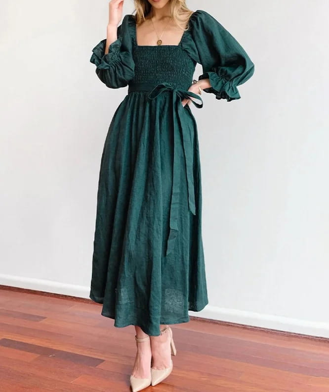 A deep emerald green reversible midi dress featuring a v-neck, long lantern sleeves, and a smocked bodice.
