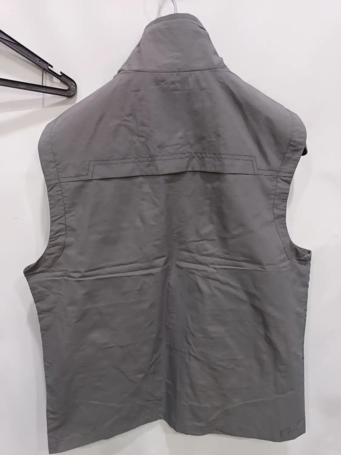 Chaleco utilitario para hombre sin mangas en color gris con cuello alto y varios bolsillos cosidos, diseñado para un uso versátil al aire libre.