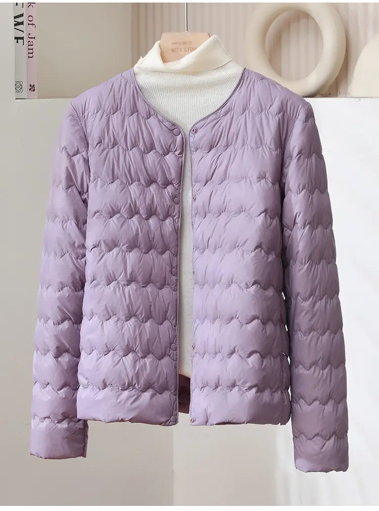 A soft lavender quilted puffer jacket with ruffled crew neck and button closure designed for warmth and style.
