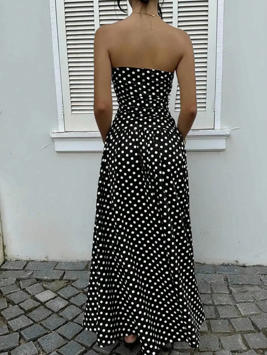 Polka dot off shoulder strapless maxi dress in black with white polka dots featuring a fitted waist and flowing skirt.