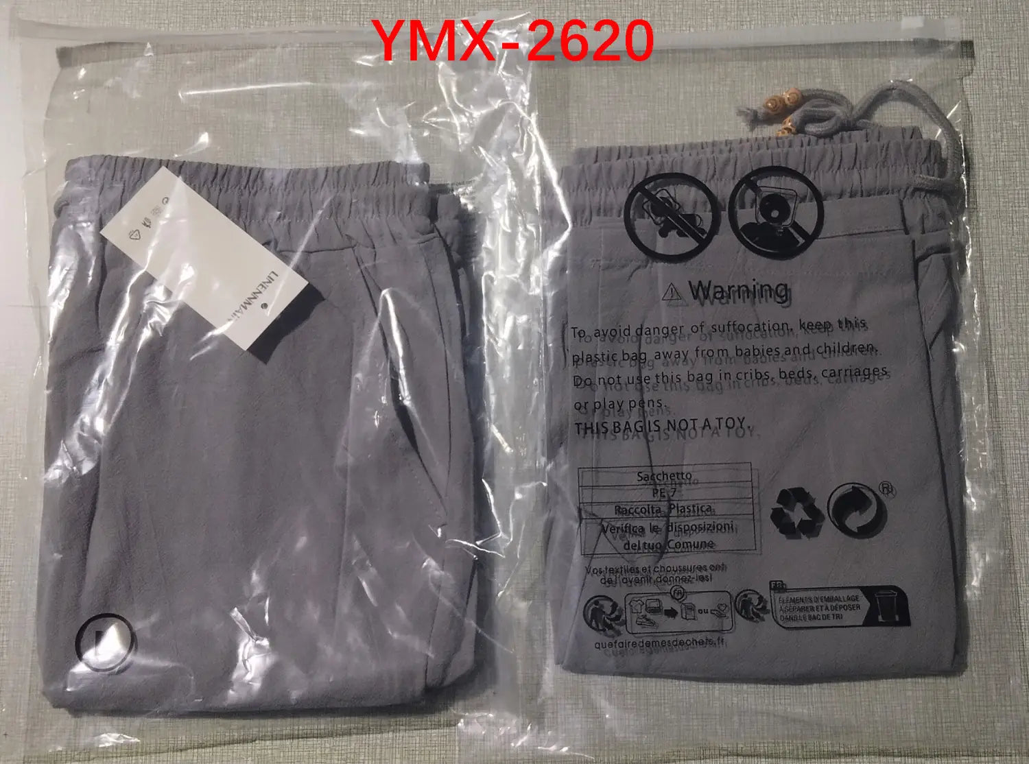 gray drawstring plastic bag with a white tag and warning label on the side containing mens cotton linen drawstring shorts.