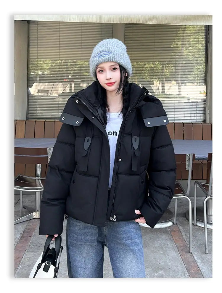 Veste courte matelassée à capuche pour femme noire, avec épaules rembourrées et poches à rabat en tissu noir, conçue pour l’habillement d’hiver chaud