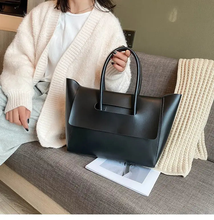 Black leather vintage structured tote bag with top handles and a defined shape for elegant carrying.