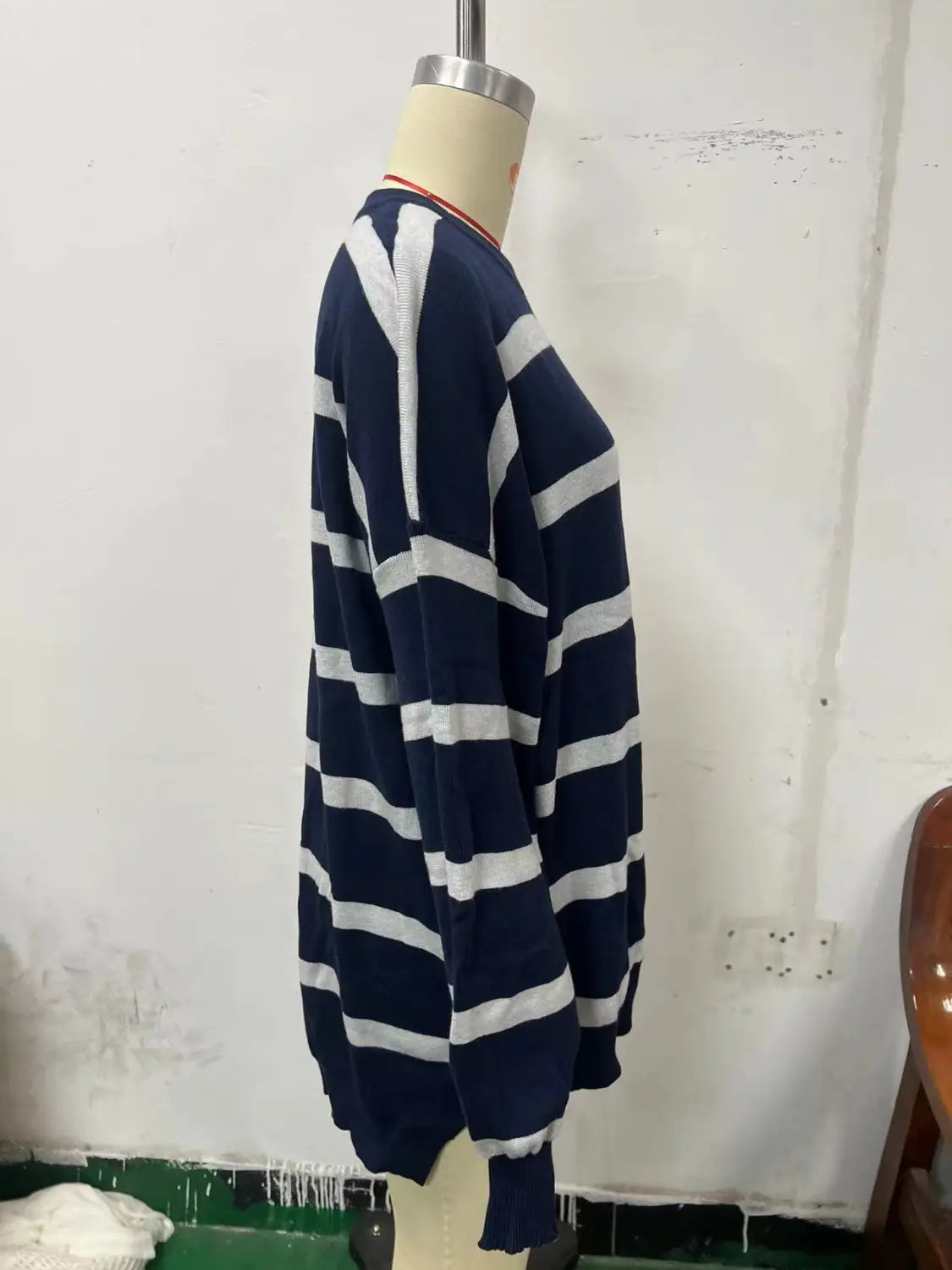 Women’s oversized split color striped knit sweater in navy blue and white with ribbed cuffs and neckline displayed from the front.