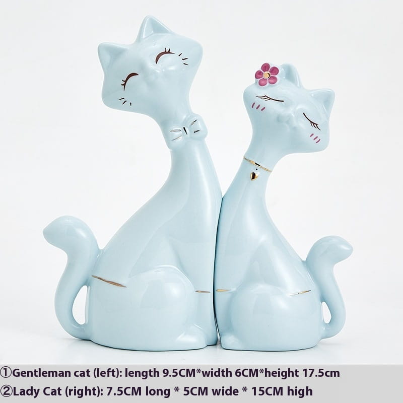 A pair of light blue ceramic cat figurines featuring a bow tie and a pink flower, suitable as modern gold and white home decor.