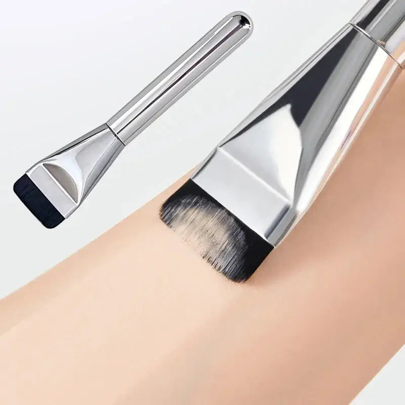 Ultra thin foundation brush with a silver-toned sleek metallic handle and dense black bristles designed as a flat traceless makeup tool.
