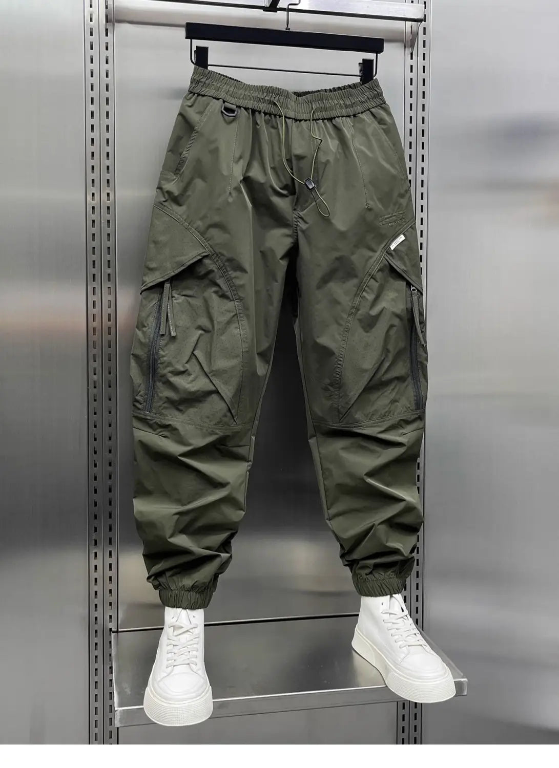Men’s tapered olive green cargo joggers with elastic waistband and drawstring, featuring multiple pockets and tapered legs.