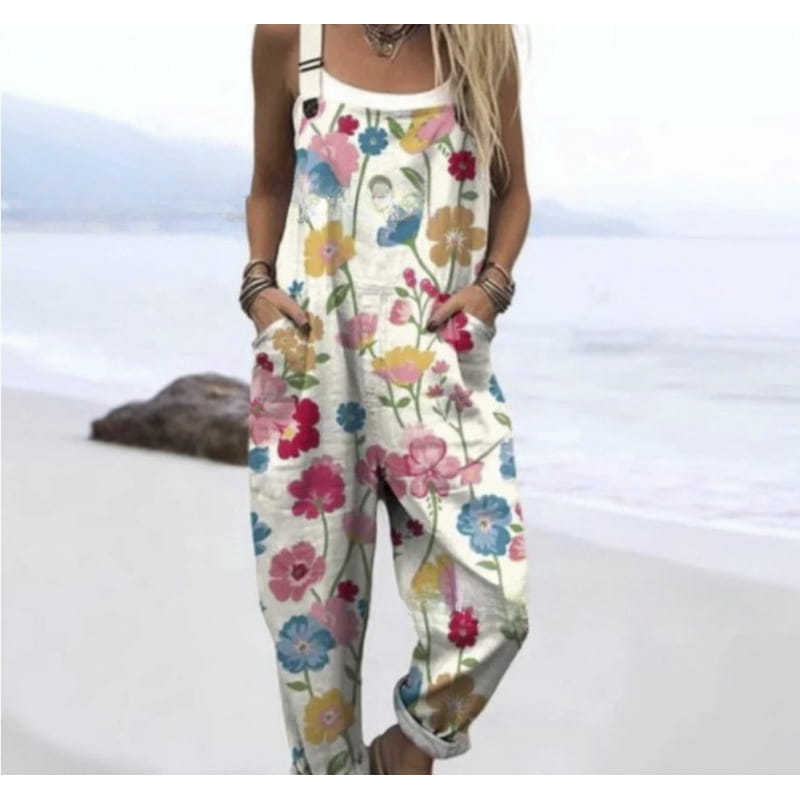 A woman wears a white floral print printed suspender overalls casual pants featuring colorful pink blue and yellow blossoms.
