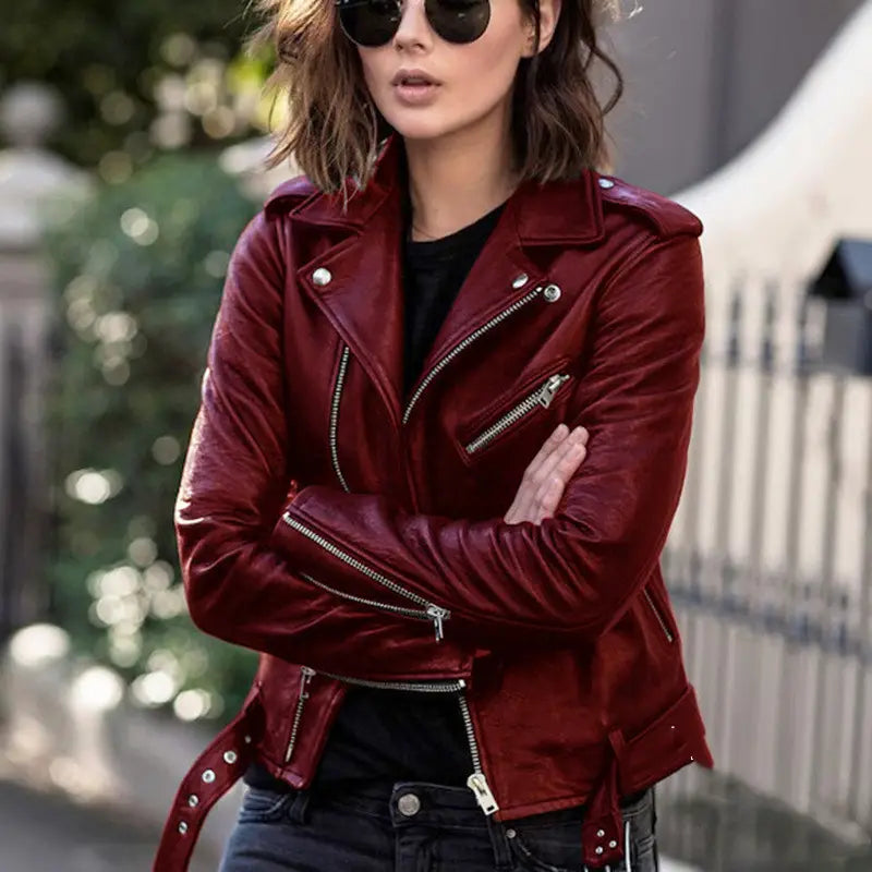Eine glänzende bordeauxrote Ledermotorradjacke mit silbernen Reißverschlüssen und Druckknöpfen.