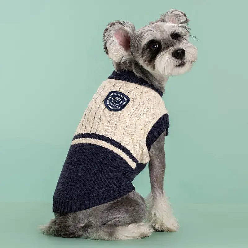 Navy- und cremefarbener Zopfmuster-Hundepullover aus warmem Material mit schildförmigem Aufnäher auf der Rückseite, im Stil einer Schuluniform, für Tierbekleidung.