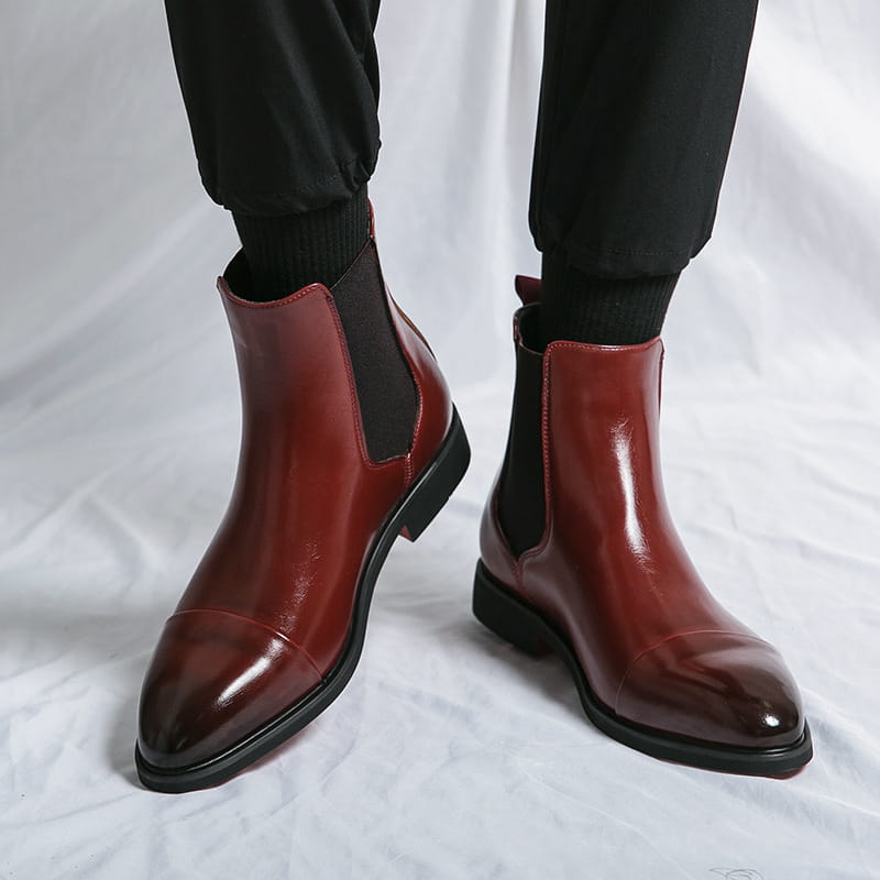 Polished burgundy leather chelsea boots with black elastic side panels and a sleek pointed toe design for men.