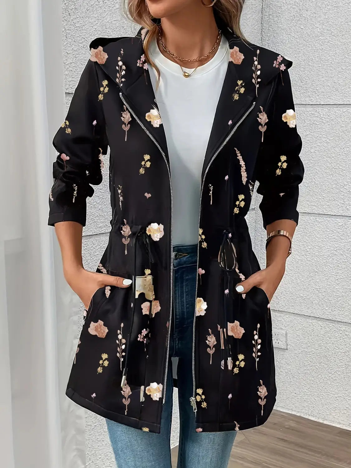 Veste à capuche zippée brodée de fleurs noire, arborant des fleurs roses et crème sur un tissu souple, idéal pour une tenue décontractée
