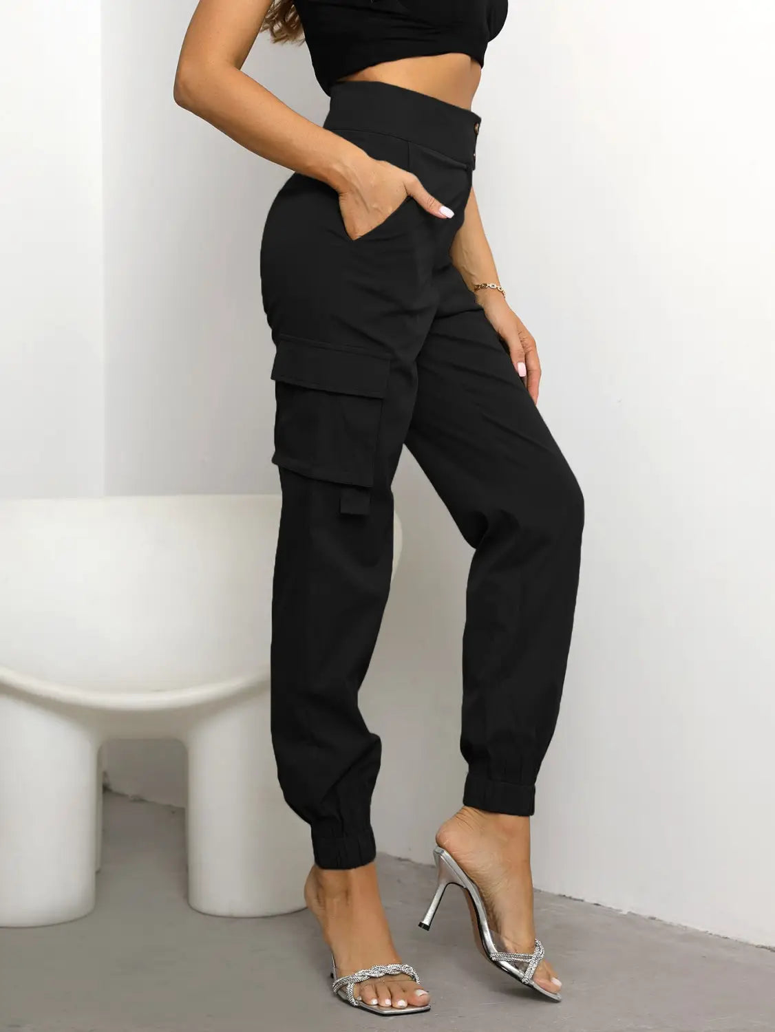 Pantalon cargo noir taille haute pour femmes en polyester, avec plusieurs poches et une jambe fuselée.