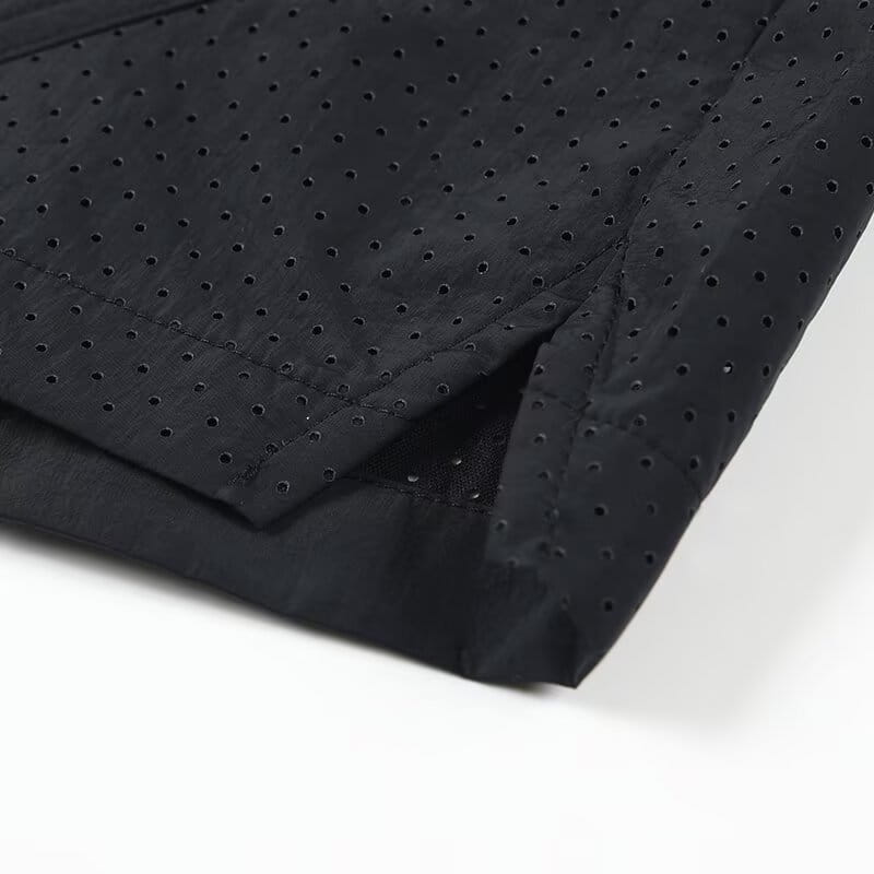 shorts en nylon décontractés pour hommes, coupe droite, en tissu noir perforé, avec une légère brillance et des ouvertures circulaires espacées uniformément pour la respirabilité.