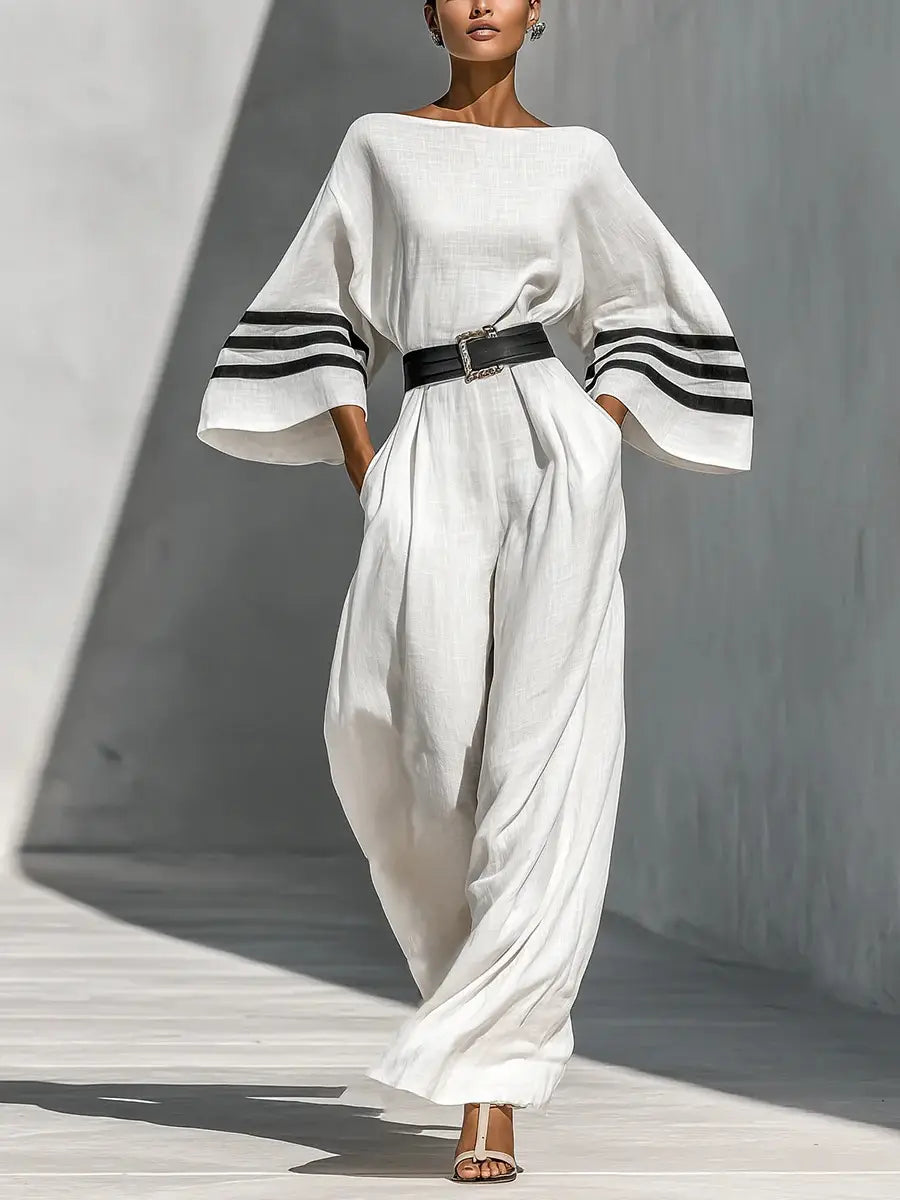 Weißer Leinen-Jumpsuit mit weitem Bein, mit schwarzen gestreiften Manschetten und passendem Gürtel.