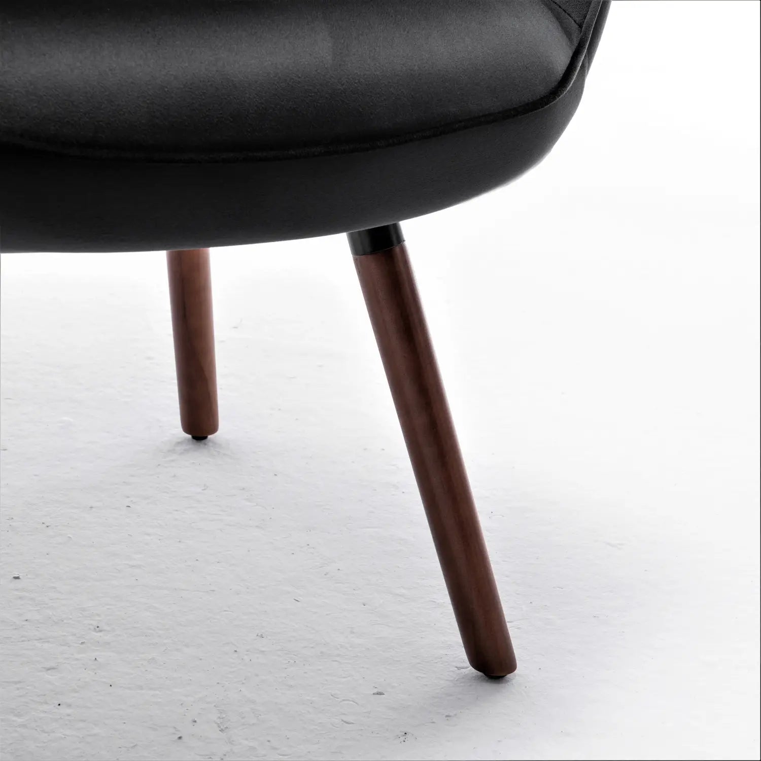 Sillón de cuero negro con patas de madera cónicas y elegantes, que ofrece un diseño contemporáneo para una cómoda y sofisticada zona de asientos decorativos.